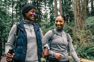 Two African American women hikers having fun, while wearing Noz-up purple and yellow odorless skunk and bear repellent sunscreen on their noses. 